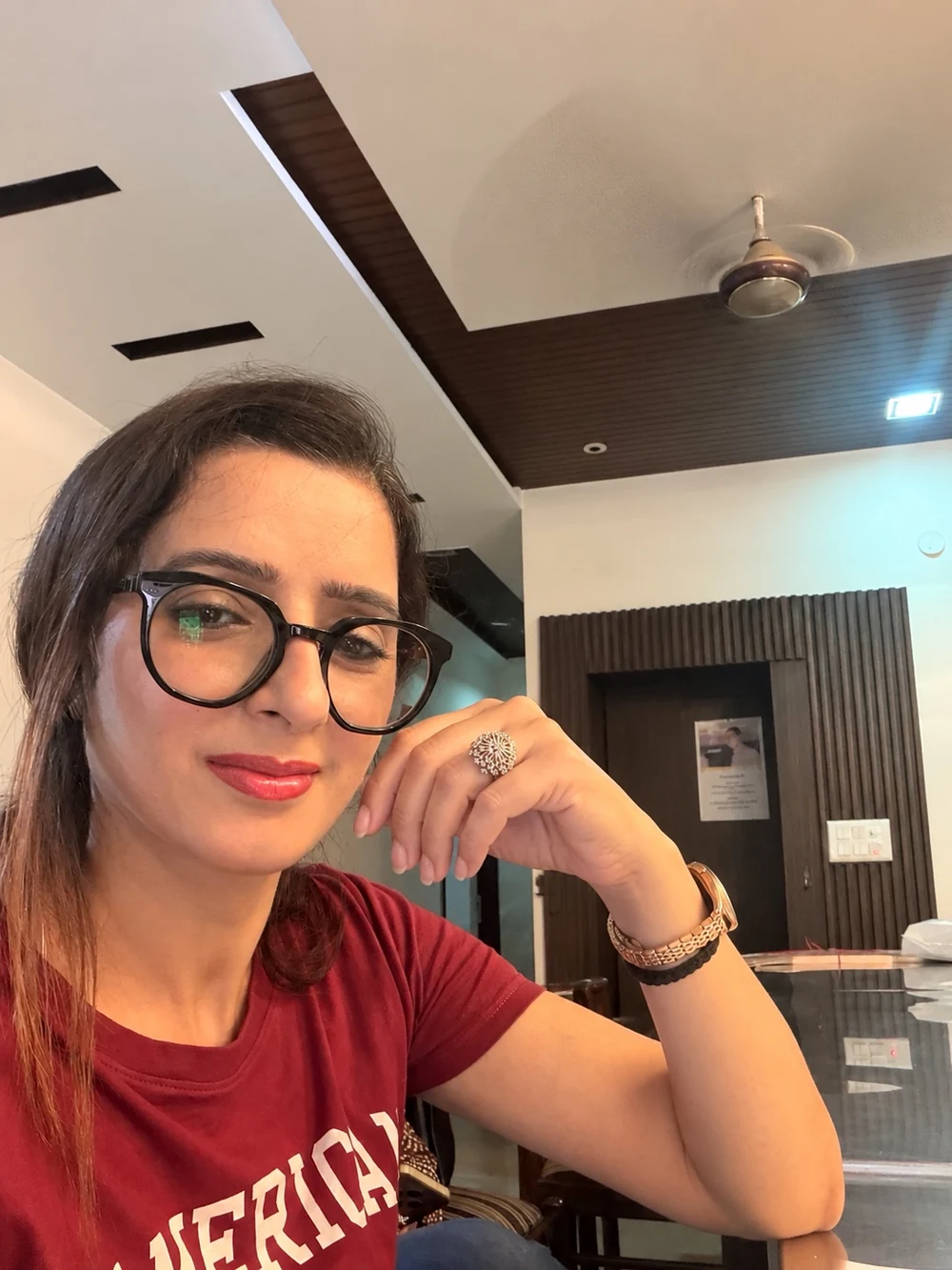 Preeti smiling in a burgundy top and glasses